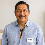 Hombre de mediana edad con camisa celeste y un electrodo de Holter 24 horas visible en el pecho, en un consultorio moderno