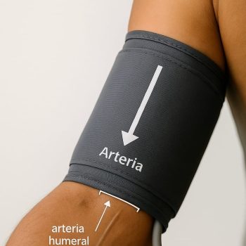 Brazo izquierdo con brazalete de tensiómetro; marca “Arteria” alineada a la arteria humeral y borde inferior a 2 cm de la flexura del codo.